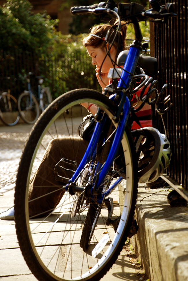 Chica sentada hablando por telefonía celular al lado de su bicicleta